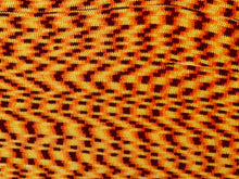 Load image into Gallery viewer, Close-up of a textured woven fabric with a repeating geometric pattern in orange, yellow, and dark brown.
