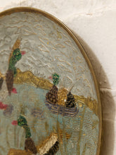 Load image into Gallery viewer, Close-up of an oval decorative wall art piece showing ducks in a reedgy pond with textured gold and blue-green detailing, mounted against a white plaster wall.
