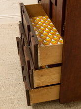 Load image into Gallery viewer, A close-up of a dark wood dresser or cabinet with multiple drawers, with two drawers pulled open to reveal colorful patterned paper inside.
