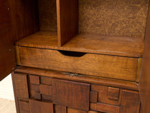 Load image into Gallery viewer, Close-up of a mid-century modern wooden cabinet with a geometric drawer design and a single pull-out drawer, shown with its door open.

