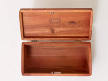 Load image into Gallery viewer, An open rectangular wooden storage box with a hinged lid, shown against a plain off-white wall. The interior and lid are made of warm reddish-brown wood with engraved branding on the inside lid reading 'LANE' and 'SCHOEN'S FURNITURE'.
