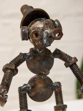Load image into Gallery viewer, A handmade metal robot figurine crafted from rusty bolts, nuts, springs, and circular metal pieces, set against a softly blurred light background.

