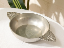 Load image into Gallery viewer, A vintage silver metal bowl with decorative leaf-shaped handles, resting on a white textured fabric surface with soft natural shadows.
