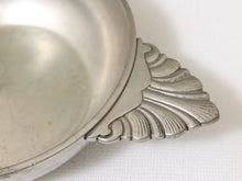 Load image into Gallery viewer, Close-up of a silver-toned metal dish or bowl with a decorative fan-shaped handle on a white textured background.
