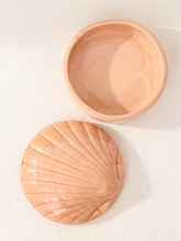 Load image into Gallery viewer, A peach-colored ceramic shell-shaped dish with its matching lid, displayed on a textured off-white background.
