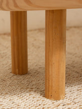 Load image into Gallery viewer, Close-up of a light natural wood table leg resting on a woven beige rug.
