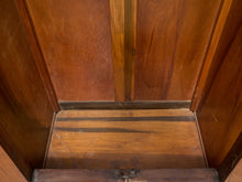 Load image into Gallery viewer, Close-up of a wooden interior with warm medium-brown panels, a central vertical wood strip, and a darker wood baseboard or floor section.
