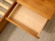 Load image into Gallery viewer, Close-up of a wooden drawer with the front pulled open, showing a light natural wood interior and a medium warm wood exterior, placed on a textured beige rug.

