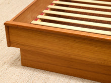 Load image into Gallery viewer, Close-up of a wooden bed frame corner with light natural wood slats on a textured beige carpet.
