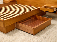 Load image into Gallery viewer, A wooden platform bed frame with slatted base and pull-out storage drawers, shown on a textured beige carpet.
