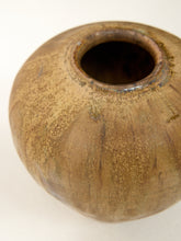 Load image into Gallery viewer, A close-up of a round ceramic vase with a textured, speckled glaze in earthy brown and beige tones, set against a plain white background.
