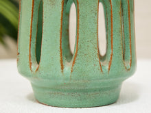 Load image into Gallery viewer, Close-up of a ceramic vase with a textured sage green glaze and vertical cutouts outlined in a warm rust-brown glaze, set against a soft neutral background.
