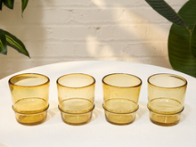 Load image into Gallery viewer, Set of four vintage amber glass tumblers with rounded sides and thick raised bases
