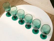 Load image into Gallery viewer, Six translucent teal-green stemmed wine glasses arranged diagonally on a round white table.
