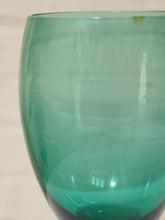 Load image into Gallery viewer, A close-up of a translucent teal green glass bowl or vase against a light beige background.
