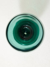 Load image into Gallery viewer, A top-down view of a round, dark green glass object, possibly a coaster or a decorative plate, on a textured off-white background.
