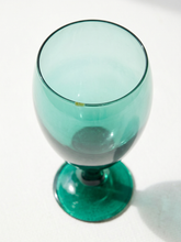 Load image into Gallery viewer, A translucent teal green glass goblet with a wide bowl and a thick circular base, photographed on a white surface with a soft shadow.
