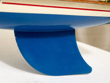 Load image into Gallery viewer, Close-up of a blue boat hull underside with a red stripe and part of a white deck, resting on a white textured surface.
