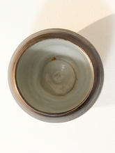 Load image into Gallery viewer, Top-down view of a ceramic cup with a matte dark gray exterior and a glossy pale green-gray interior, set against a white background with a soft shadow.
