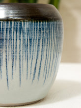 Load image into Gallery viewer, Close-up of a ceramic planter or vase with a glossy dark brown top and vertical blue glaze drips on a white base, set against a softly blurred neutral background.
