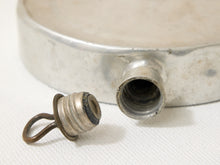 Load image into Gallery viewer, A close-up of a vintage silver metal canteen or flask with its threaded cap removed, showing the opening and a small metal loop attached to the cap, set against a white textured fabric background.
