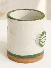 Load image into Gallery viewer, A handmade ceramic mug with a speckled off-white glaze, a dark green rim, a green band near the base, and a brown clay foot, shown on a white textured surface.

