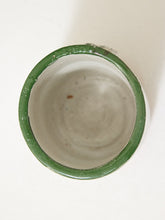 Load image into Gallery viewer, A top-down view of a handmade ceramic cup with a glossy green rim and a matte off-white interior, set against a plain off-white background.

