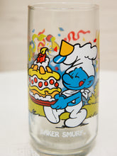Load image into Gallery viewer, A clear glass beer tumbler featuring a colorful cartoon illustration of a blue Smurf dressed as a baker carrying a birthday cake, with the text 'BAKER SMURF' printed near the bottom.
