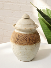 Load image into Gallery viewer, Vintage lidded ceramic jar with carved brown leaf pattern, speckled cream glaze, and tiered finial
