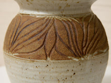 Load image into Gallery viewer, Close-up of a handmade ceramic vase with a textured, speckled cream glaze and a central band of raised brown leaf patterns.
