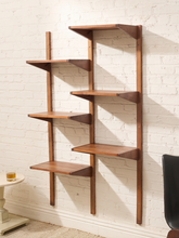Load image into Gallery viewer, A mid-century modern wall-mounted wooden bookshelf with five tiers, shown against a white brick wall in a room setting.
