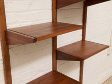 Load image into Gallery viewer, Mid-century modern wall-mounted wooden shelving unit with a rich walnut-brown finish, featuring cantilevered shelves against a white painted brick wall.
