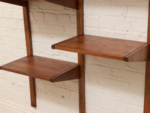 Load image into Gallery viewer, Mid-century modern wall-mounted wooden shelving with three tiers of warm brown shelves and matching vertical supports, set against a white painted brick wall.
