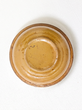 Load image into Gallery viewer, A small round ceramic bowl viewed from directly above, featuring a warm tan and brown glaze on a white textured fabric background.

