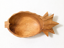 Load image into Gallery viewer, A handcrafted wooden bowl shaped like a pineapple, featuring a smooth, rounded body and a textured, multi-pointed crown on the side, photographed on a white textured fabric background.

