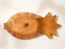 Load image into Gallery viewer, A hand-carved wooden pineapple-shaped dish or tray with a natural warm brown finish, resting on a textured off-white fabric background.
