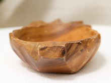 Load image into Gallery viewer, A small hand-carved wooden bowl with a faceted, geometric exterior and a smooth, rounded interior, shown on a white textured surface.
