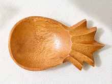 Load image into Gallery viewer, A hand-carved wooden spoon with a decorative leaf-like handle, made from light brown wood with visible grain, resting on a textured off-white fabric background.

