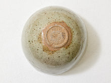 Load image into Gallery viewer, A ceramic bowl viewed from above, featuring a speckled sage green and gray glaze with a prominent brown clay center under the rim, set against a white textured fabric background.
