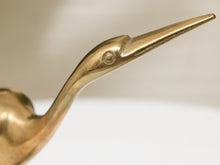 Load image into Gallery viewer, Close-up of a polished brass heron figurine showing its long beak, eye, and part of its body against a soft neutral background.
