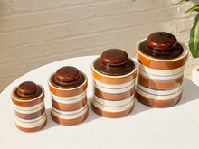 Load image into Gallery viewer, Set of four vintage striped stoneware canisters with brown lids and cream blue and brown bands

