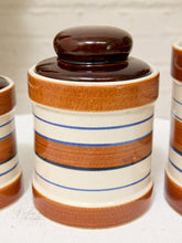 Load image into Gallery viewer, A ceramic canister with a matching lid, featuring a glossy dark brown top and base, and a cream body with horizontal blue stripes.
