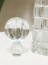 Load image into Gallery viewer, A clear glass or acrylic decorative object with a faceted round top and short cylindrical base, shown on a light surface with a blurred matching object in the background.

