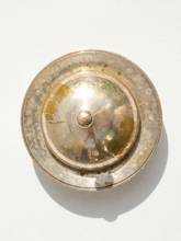 Load image into Gallery viewer, A round, vintage silver-toned metal object with a domed center and a textured, aged rim, photographed from directly above on a white background.

