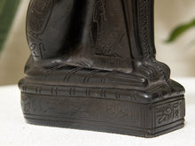 Load image into Gallery viewer, Close-up of a dark carved figurine or statue base with Egyptian-style hieroglyphic engravings, photographed on a light surface with a softly blurred background.
