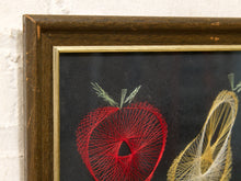Load image into Gallery viewer, A close-up of a framed string art piece featuring a red apple design with green stems and part of a yellow abstract design on a dark background, set in a dark wood frame.
