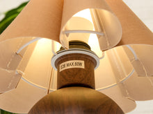 Load image into Gallery viewer, Close-up of a table lamp with a warm beige fabric shade, a wooden neck, and a visible label reading 'E26 MAX.60W'.
