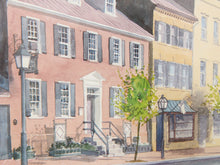 Load image into Gallery viewer, Watercolor painting of a historic street scene featuring a pinkish-red brick house with gray shutters, a yellow building, a green tree, and a black street lamp.
