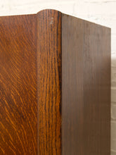 Load image into Gallery viewer, Close-up of a wooden cabinet corner showing a warm medium-brown wood grain finish against a white brick wall background.
