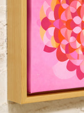 Load image into Gallery viewer, Close-up of a framed canvas print featuring a colorful abstract floral design in shades of pink, red, orange, and yellow, set in a light natural wood frame against a textured off-white wall.
